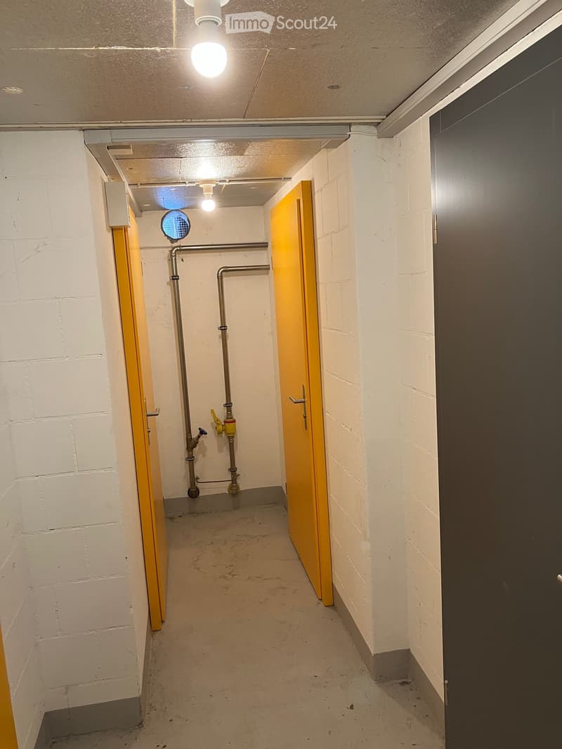 {"type": "Corridor", "description": "Industrial corridor with two yellow doors and a piped wall, lit by overhead light fixtures.", "visible_features": []}
