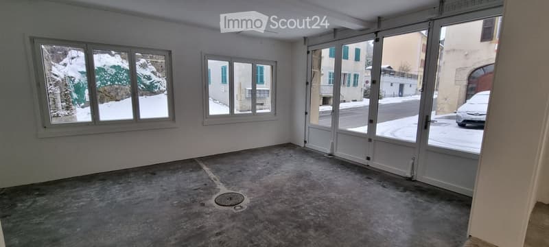 Empty room with concrete floor, large windows, and sliding glass doors leading to a snowy outdoor area.