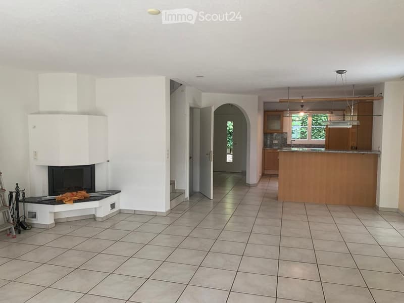 Open-plan living and dining area with a fireplace, bar counter, and adjacent kitchen area with cabinets and sink.