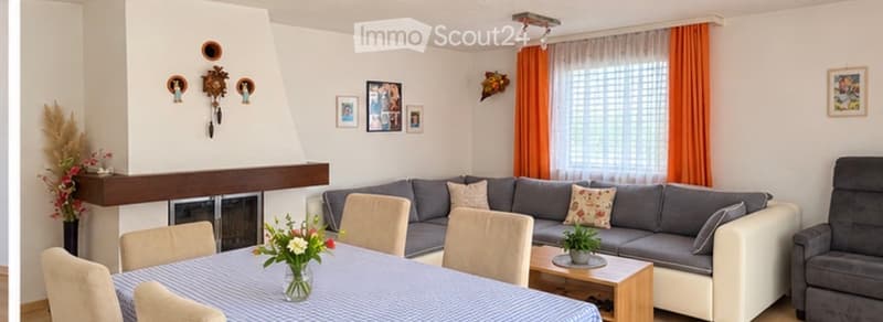 Living room with grey sectional sofa, coffee table, armchair, dining table with chairs, fireplace, and decorative items.