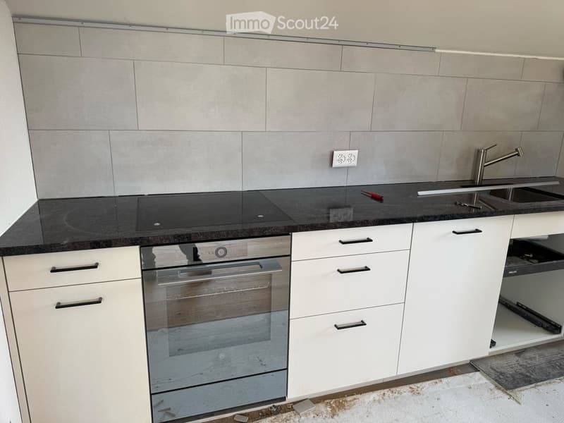 White cabinetry, black countertops, integrated oven, sink with faucet, power outlet, pull-out drawer