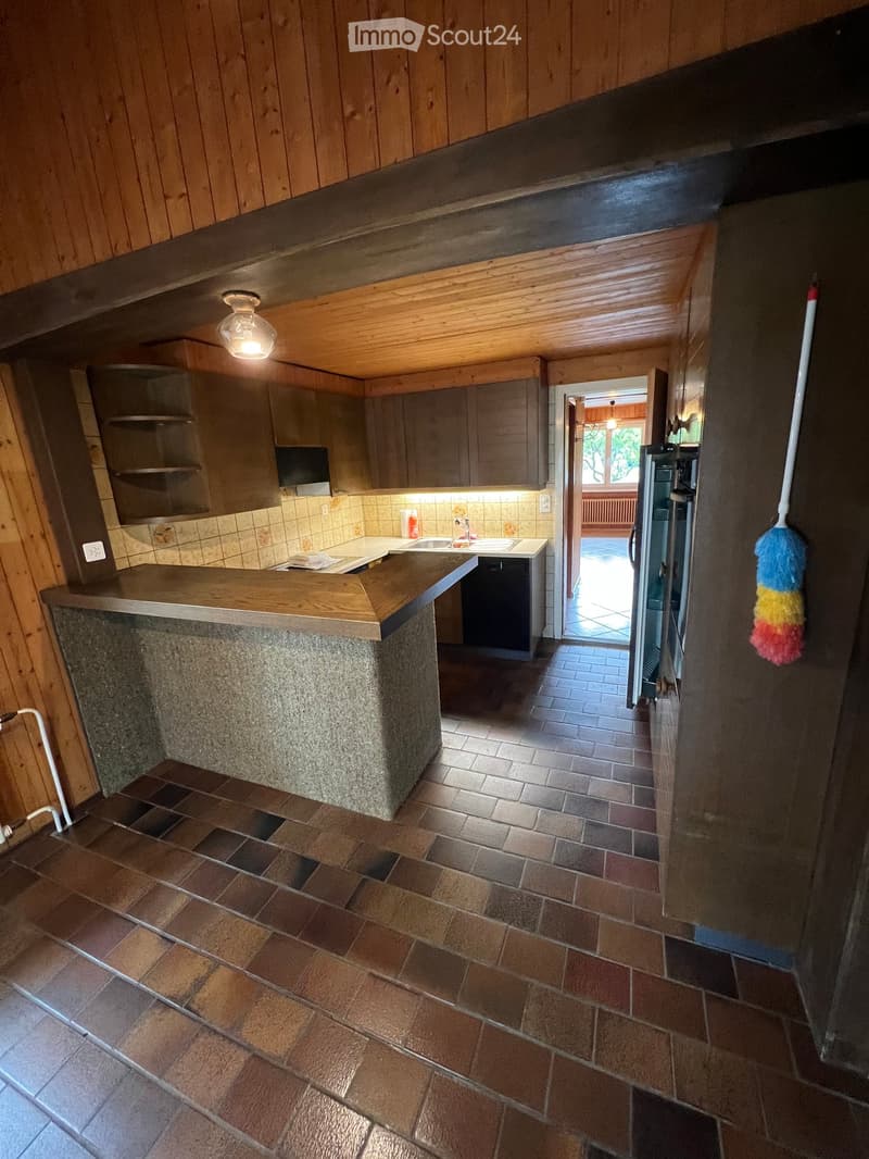 Kitchen with wooden walls, tiled floor, central island counter, sink, and appliances.