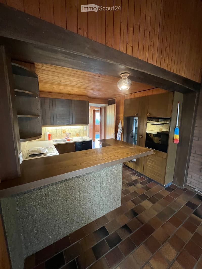 Modern kitchen with wooden cabinets, granite countertop, tiled floor, and stainless steel appliances including a sink, oven, and refrigerator.