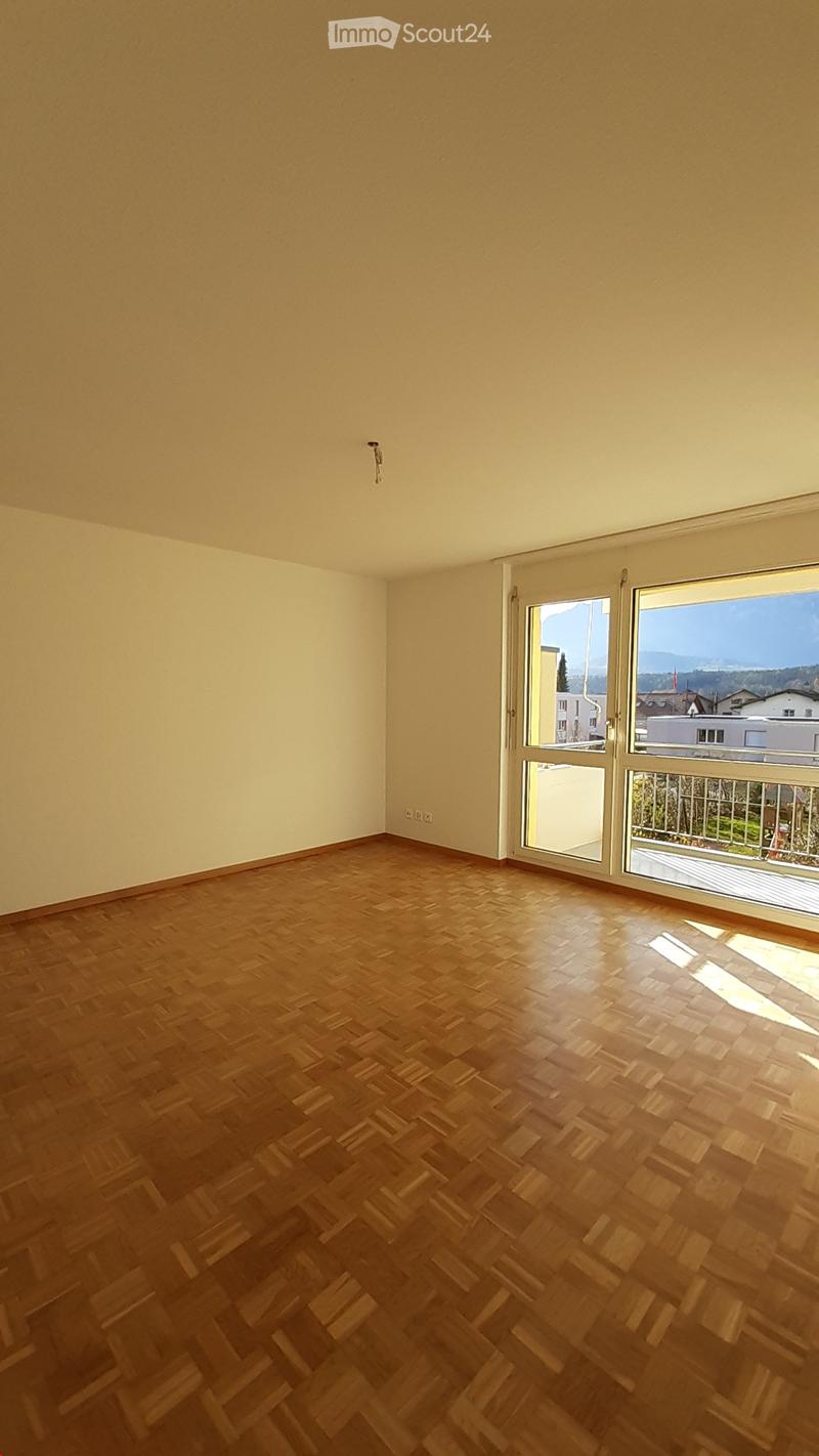 Empty room with wooden flooring and large windows offering a scenic view of the surrounding area.