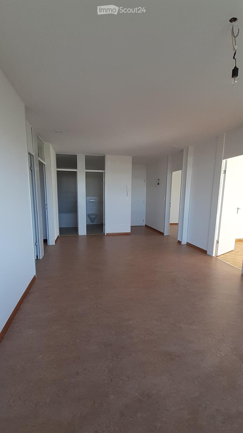 Empty room with concrete floor, white walls, and open doorways leading to a small bathroom and another room.