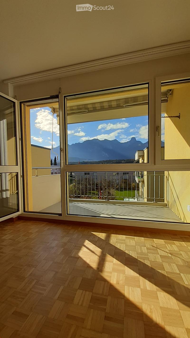 Empty room with wooden flooring, large windows, and a view of mountains and sky.