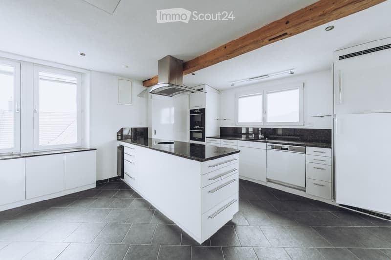 Modern kitchen with white cabinets, black countertops, stainless steel appliances, and large windows.