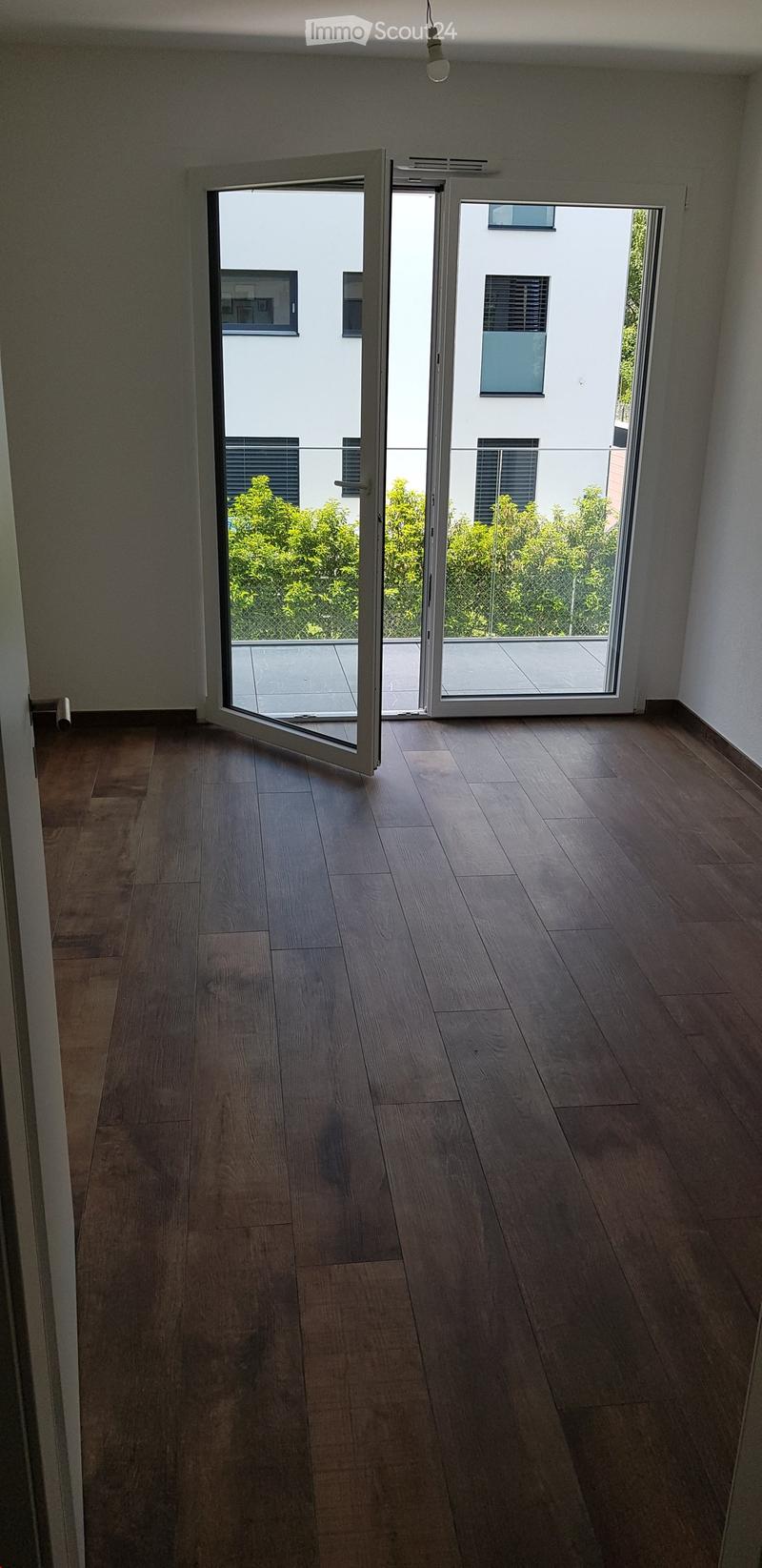 Empty room with wooden flooring and large sliding glass doors leading to a balcony or terrace area.