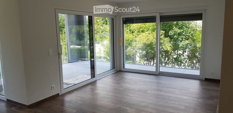 Empty room with wooden flooring and large sliding glass doors leading to a balcony or terrace area.