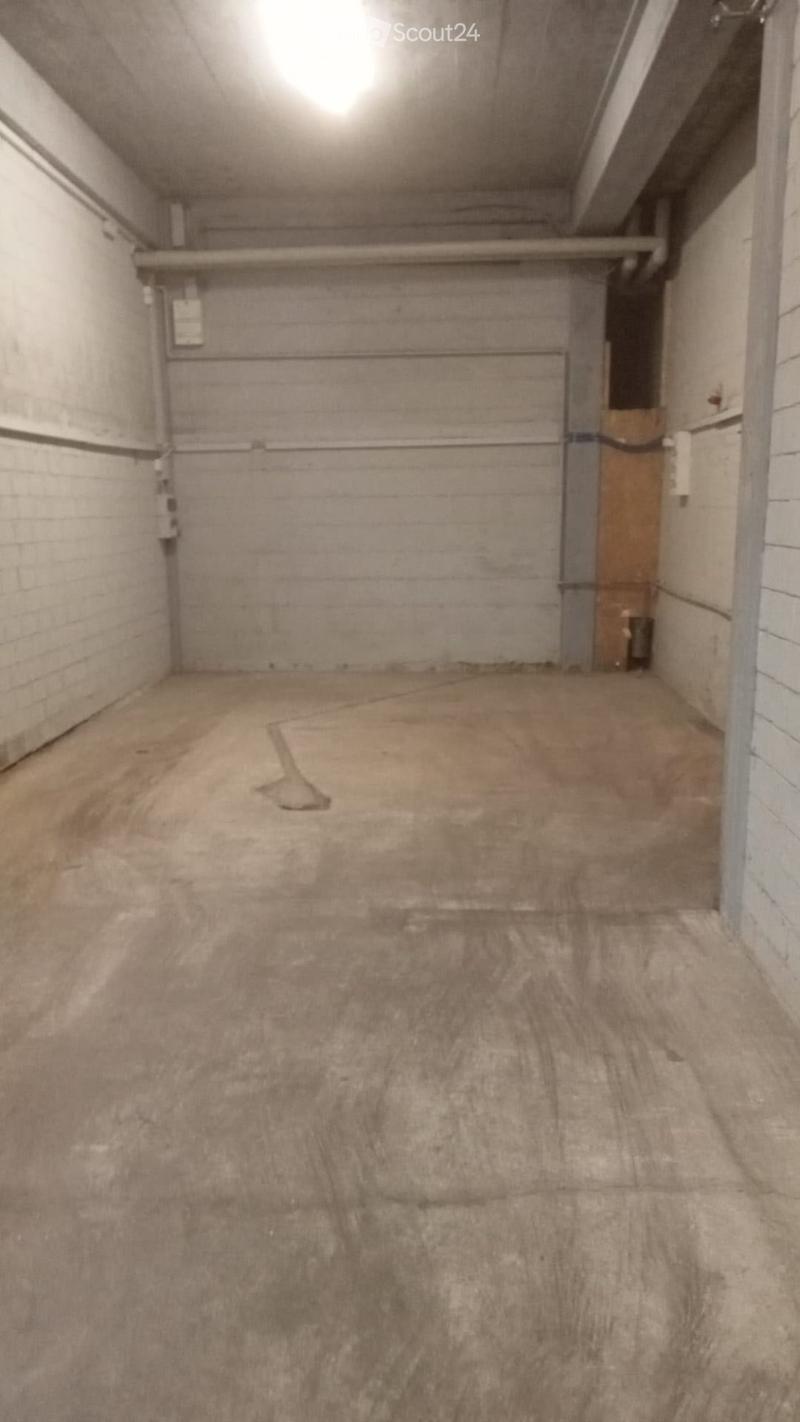 Empty garage with concrete floor, brick walls, and a large closed garage door. No furniture or equipment present.