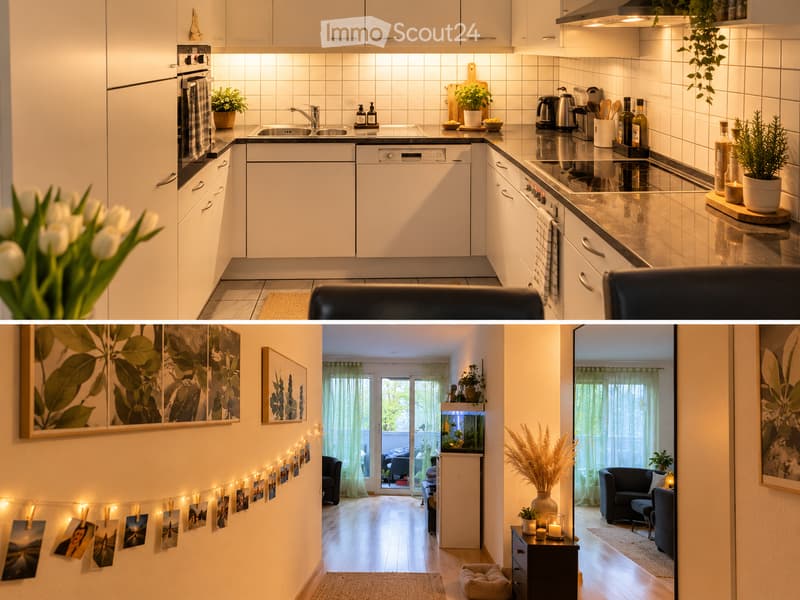 Modern kitchen with white cabinets, stainless steel appliances, and a sleek countertop. The living area features a fish tank, a sofa, and a small table with a lamp.