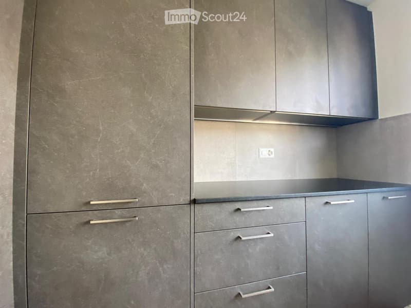 Modern kitchen with grey cabinets and drawers, featuring sleek metallic handles and a clean, minimalist design.