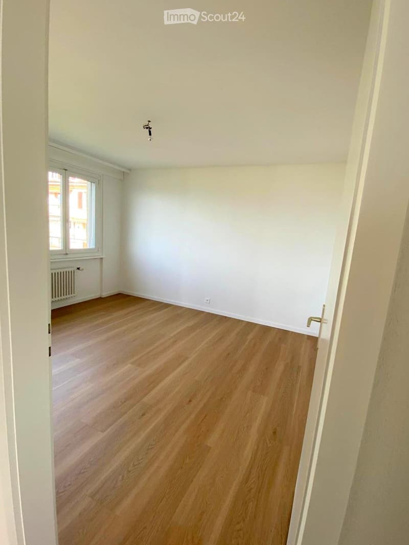Empty room with light wooden flooring, white walls, and a window with blinds. No furniture or equipment is present.