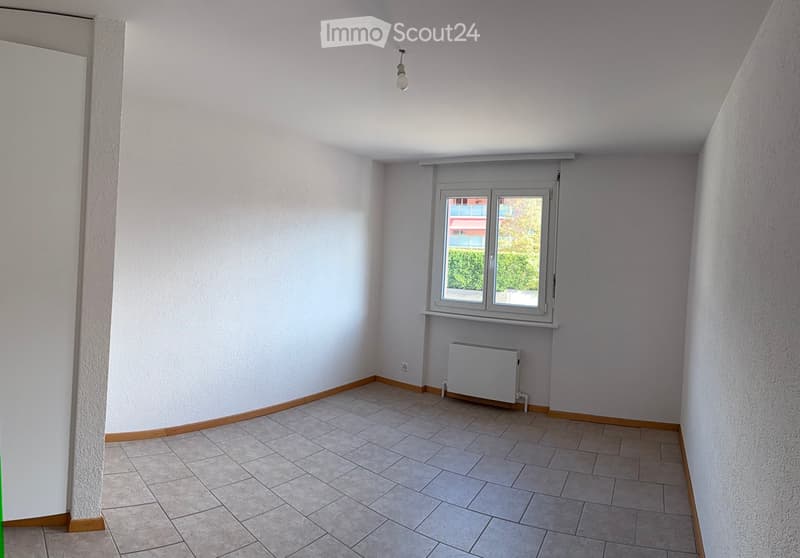 Empty room with tiled floor, white walls, a window with blinds, and a radiator below the window.