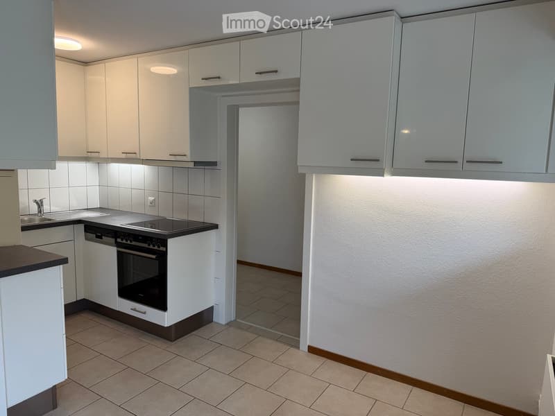 Modern kitchen with white cabinets, stainless steel appliances, and tiled flooring.