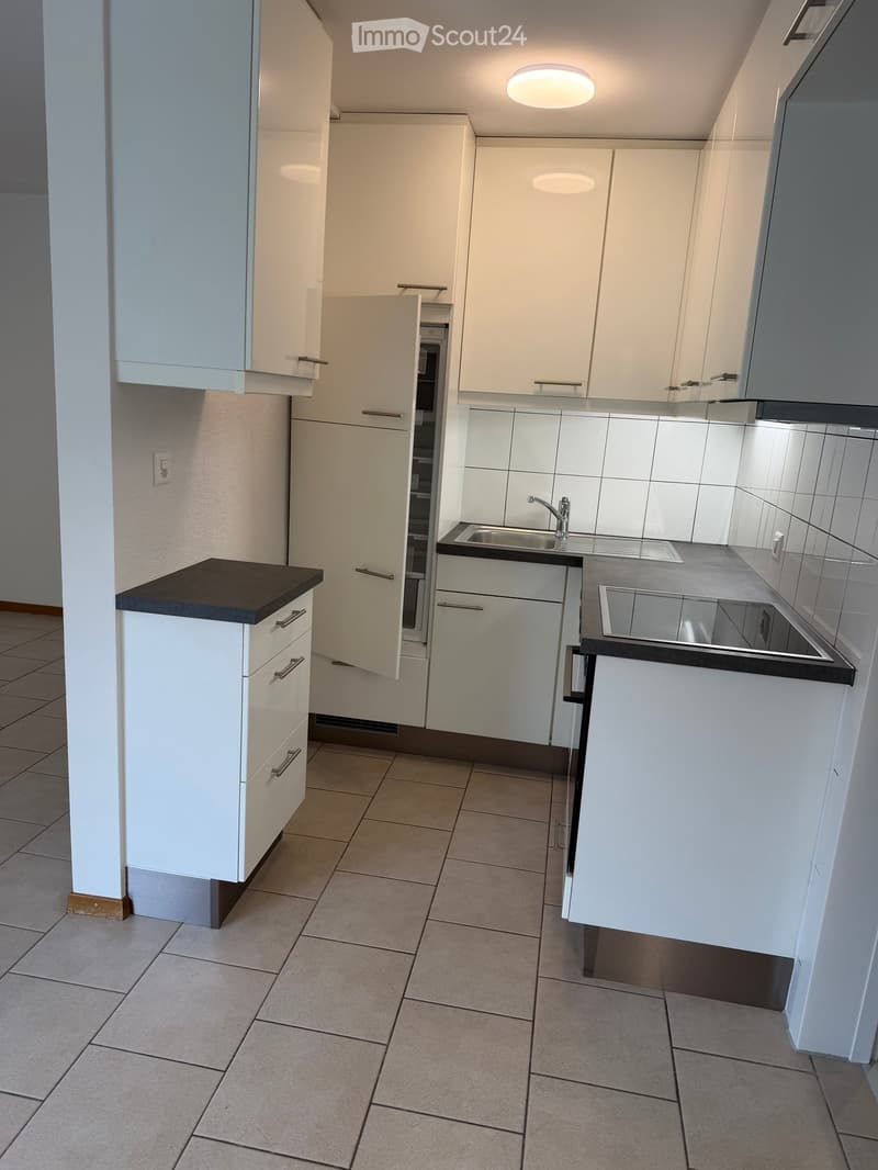 Modern kitchen with white cabinets, tiled floor, and stainless steel sink.