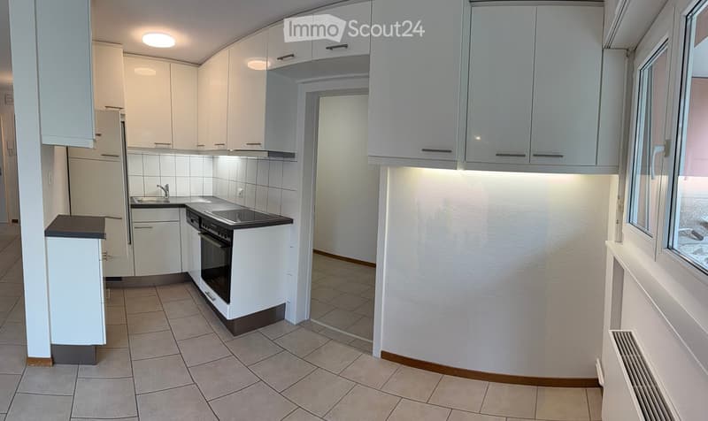 Modern kitchen with white cabinets, tiled walls, and a black countertop. Features include a sink, faucet, and built-in oven.