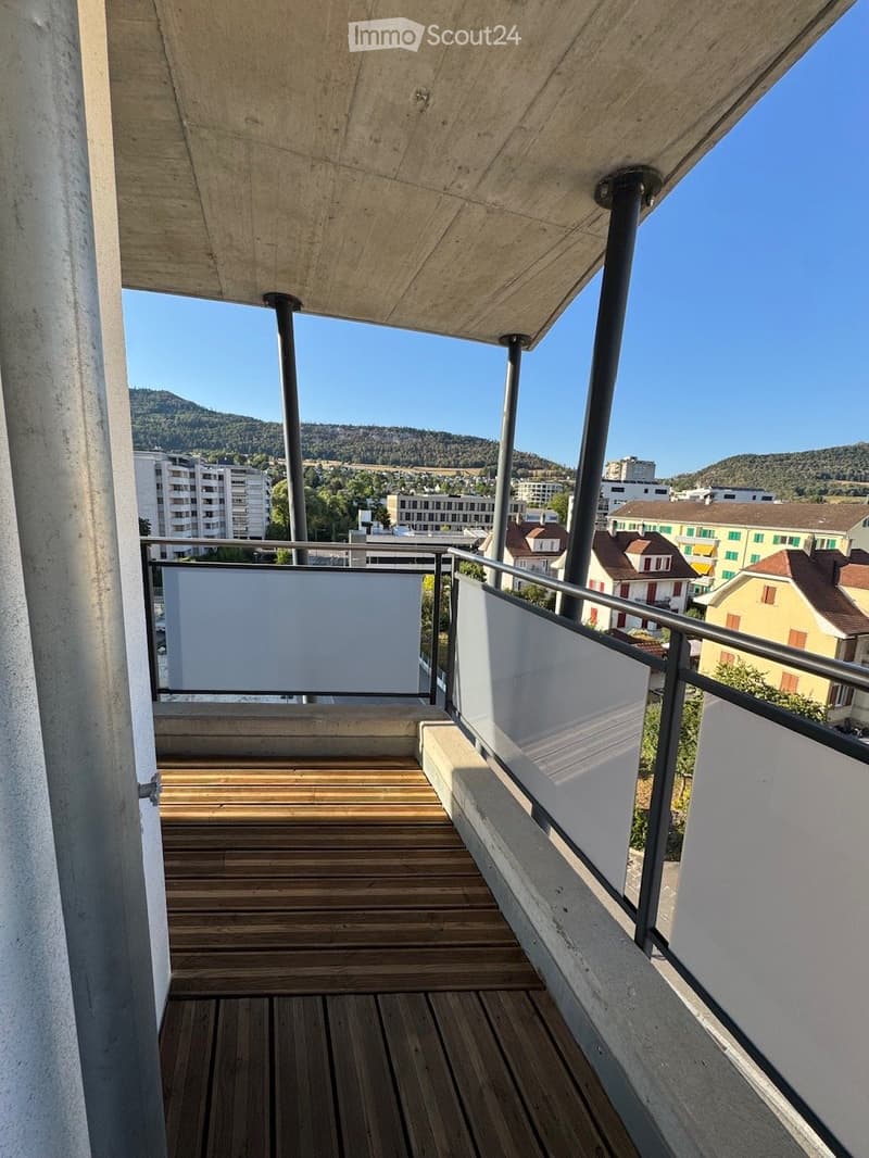 Balcony with wooden decking, white privacy screens, metal railing, and a view of the city and surrounding hills.