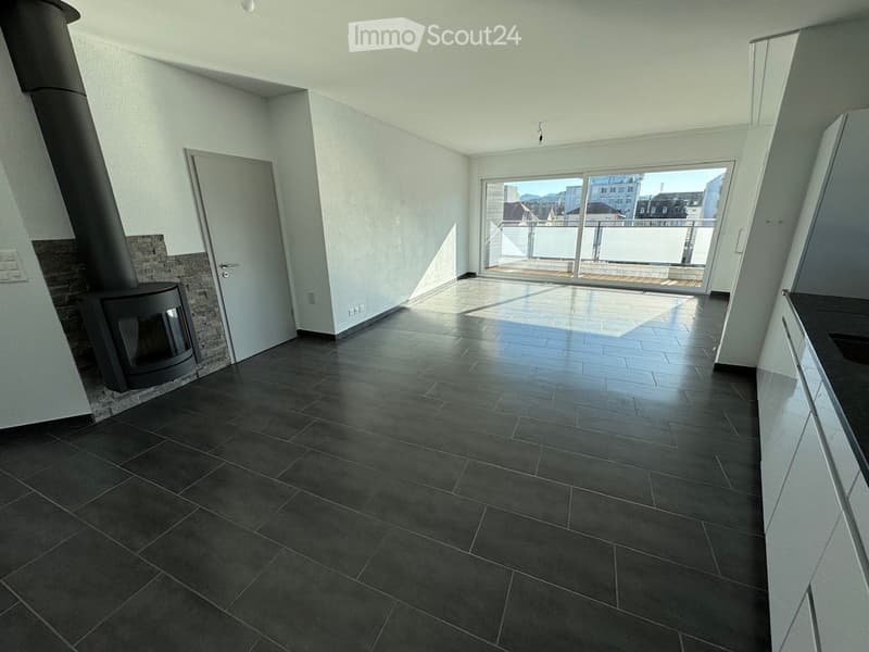 Empty room with dark tiled floor, white walls, fireplace, and large sliding glass door leading to a balcony.