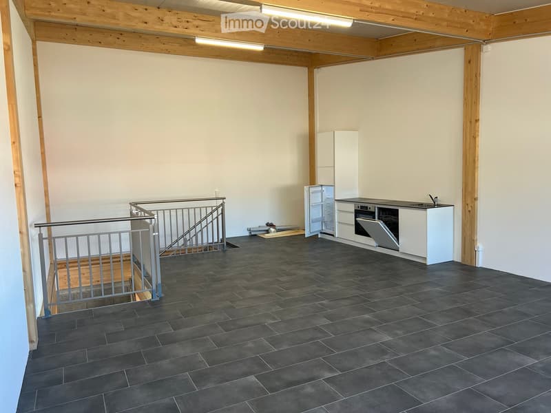Modern kitchen with dark tiled floor, white cabinets, stainless steel appliances, and a staircase leading upwards.