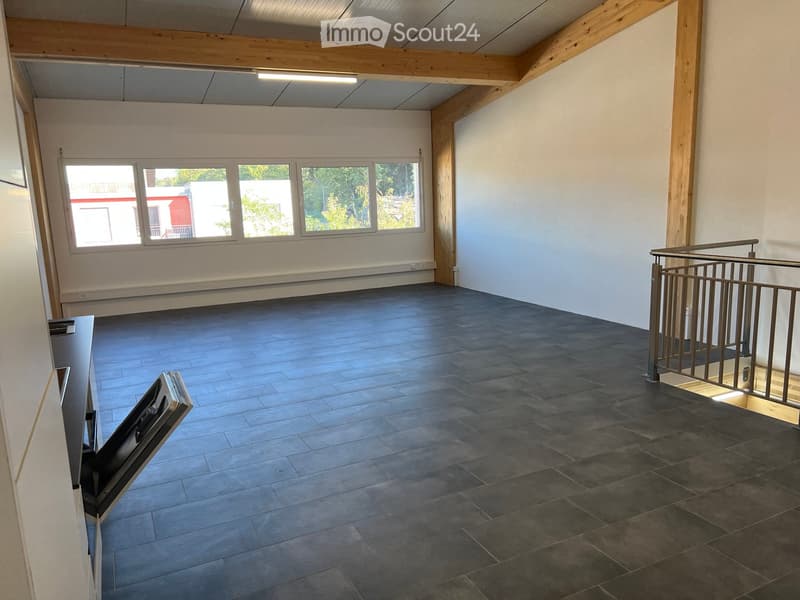 Empty room with dark tiled floor, white walls, large windows, and a metal staircase railing leading to an upper level.