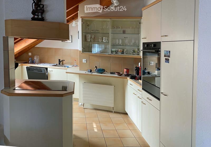 Modern kitchen with white cabinets, a glass display cabinet, stainless steel appliances, and a wooden countertop.