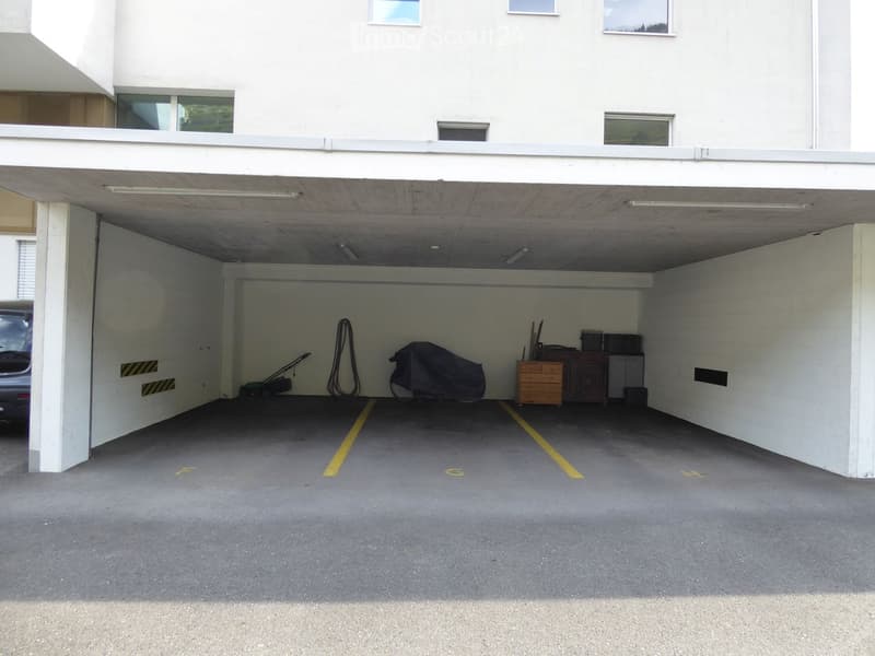 {"type": "Garage", "objects": ["car", "lawn mower", "storage cabinet", "covered object"], "description": "Underground garage with concrete floor, white walls, and yellow parking lines. Contains a car, a covered object, a lawn mower, and a small storage ca