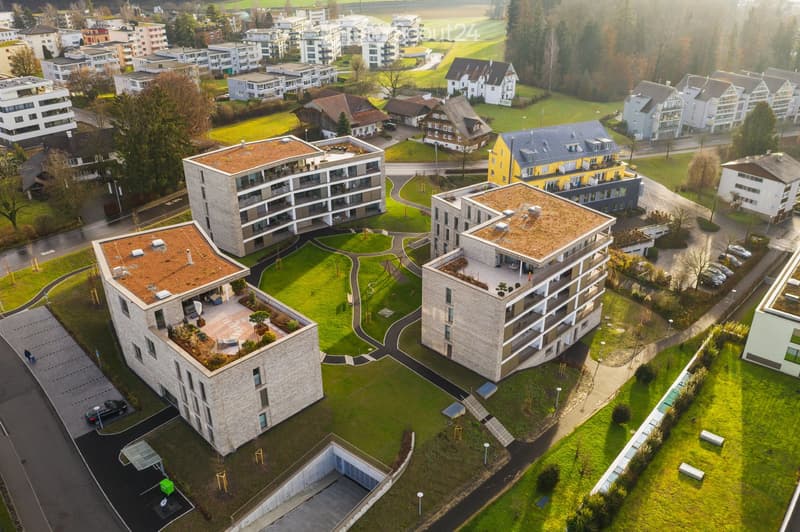 Aerial view of a modern residential complex with multiple buildings, green spaces, and parking areas.