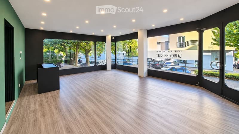 Empty room with wooden flooring, large windows, and modern lighting fixtures. No furniture or equipment present.