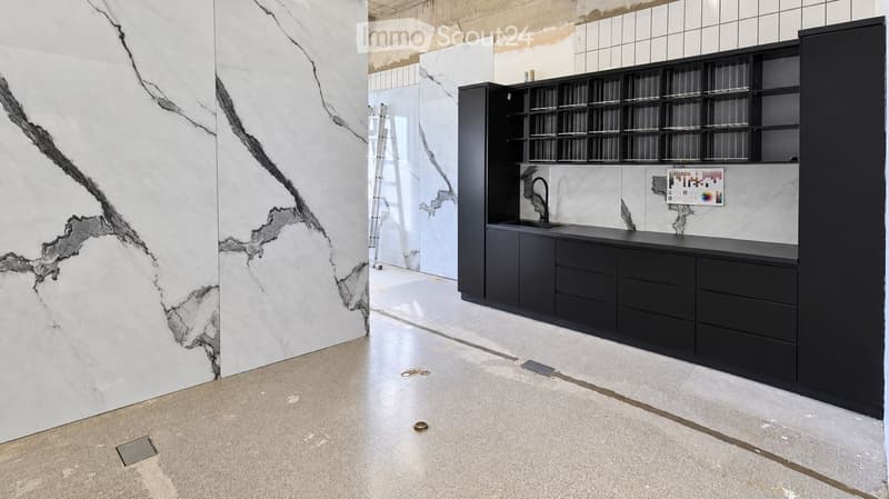 Modern kitchen with black cabinets, a sleek sink, and a marble accent wall. The space is clean and contemporary with a minimalist design.