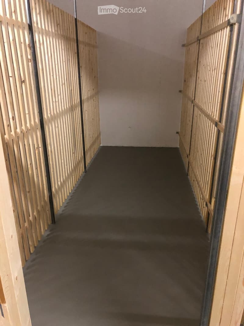 Empty hallway with wooden paneling on both sides and a dark carpeted floor.