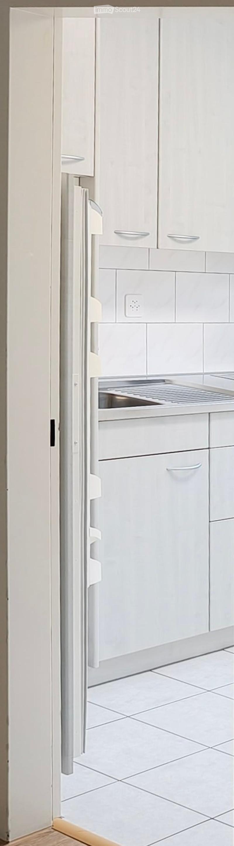 Modern kitchen with white cabinets, a stainless steel refrigerator, and tiled flooring.