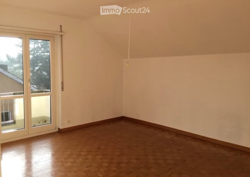 Empty room with wooden flooring, white walls, and large sliding glass doors leading to an outdoor area.