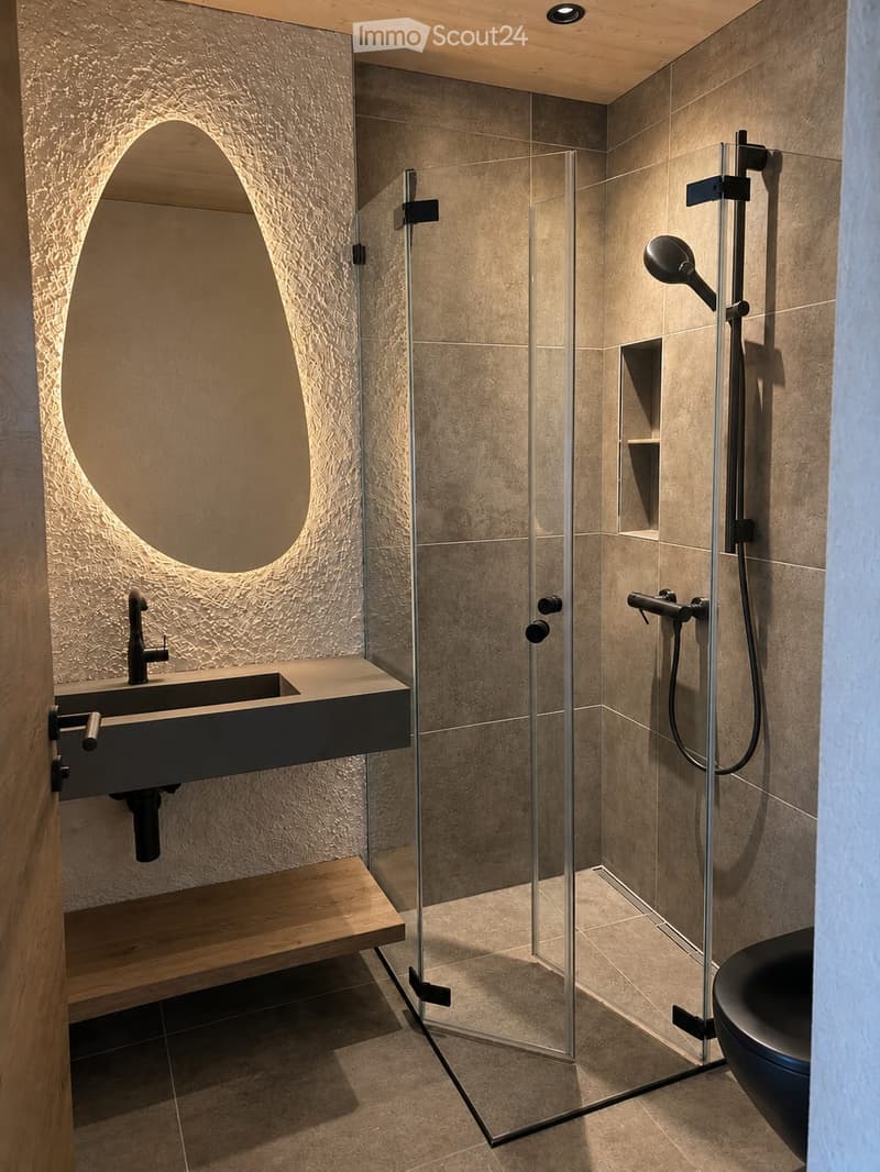 Modern bathroom with a sleek sink, glass-enclosed shower, and a dark-toned bathtub. Features include a textured wall, a built-in wooden shelf, and a large, curved mirror.