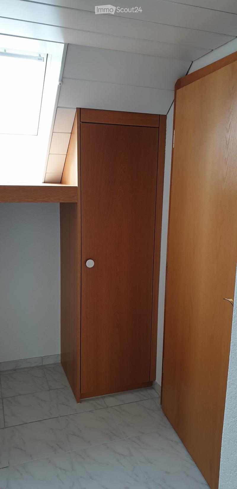 A narrow hallway with marble flooring, white walls, and wooden doors on both sides. A small built-in shelf is visible on the left wall near a window.