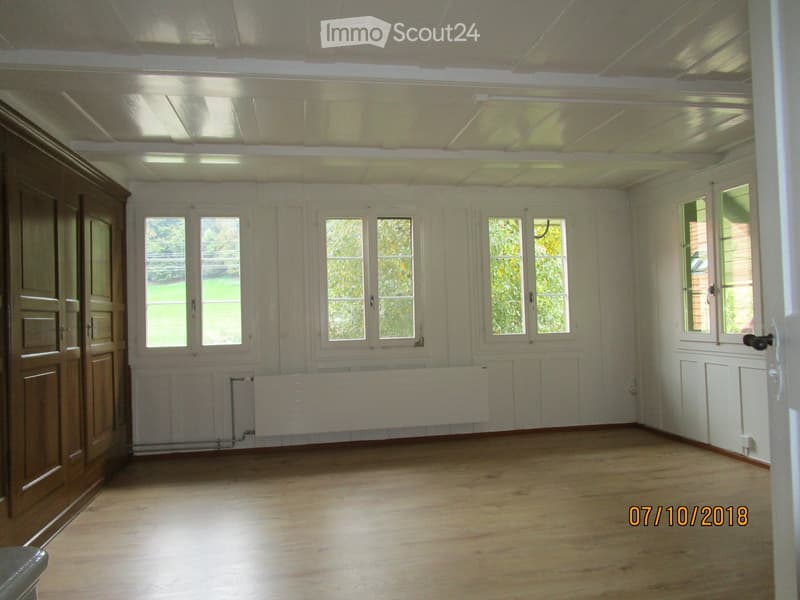 Empty room with wooden flooring, white walls, multiple windows, and a radiator. No furniture or equipment present.
