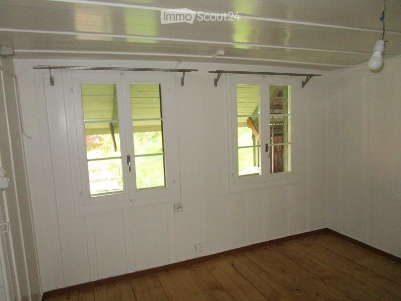 Empty room with wooden flooring, white paneled walls, and white sliding doors with glass panels.