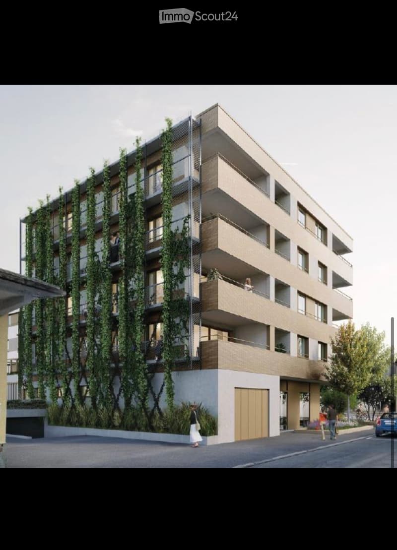Modern multi-story residential building with balconies, greenery on the facade, and a contemporary design.