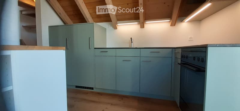 Modern kitchen with light blue cabinets, wooden countertops, and stainless steel appliances including a sink and oven.
