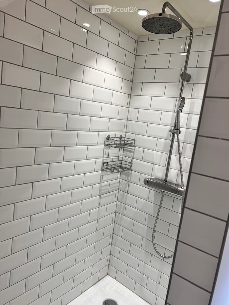 Modern shower with white subway tiles, a handheld showerhead, and a built-in shelf for toiletries.