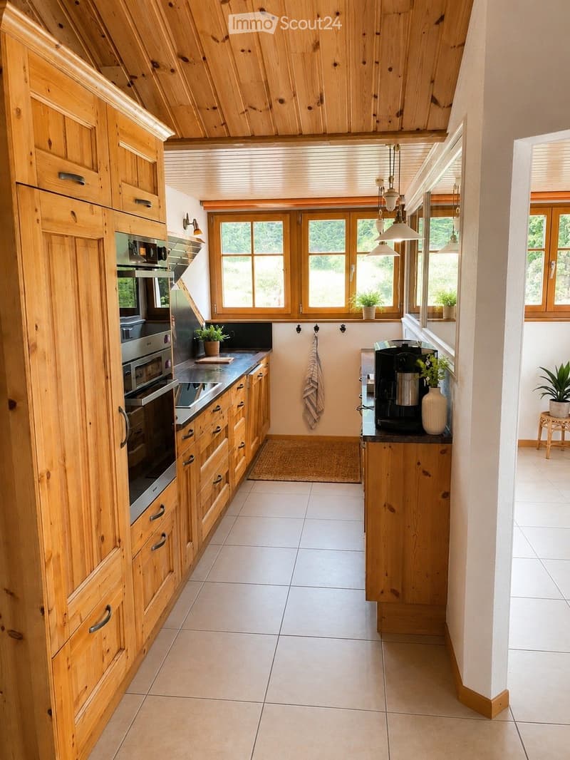 Bright kitchen with wooden cabinets, stainless steel appliances, and a central island. Features pendant lights, potted plants, and a cozy rug.