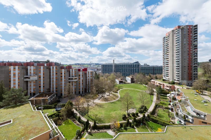 A large green space with pathways, trees, and a playground area, surrounded by residential buildings and apartment complexes.
