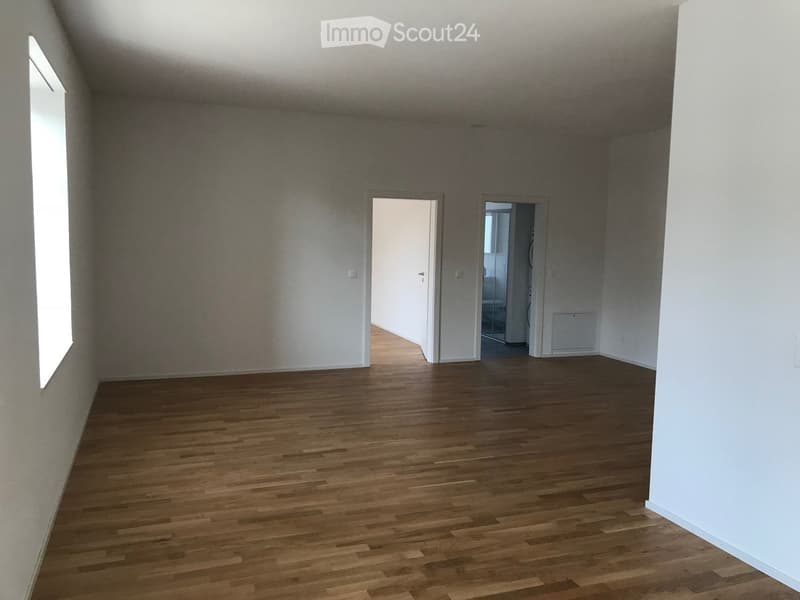 Empty room with wooden flooring, white walls, and two open doorways leading to other spaces.