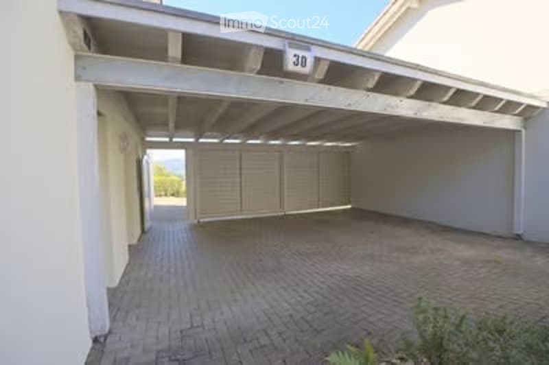 Garage with a tiled floor, white walls, and a large overhead door.