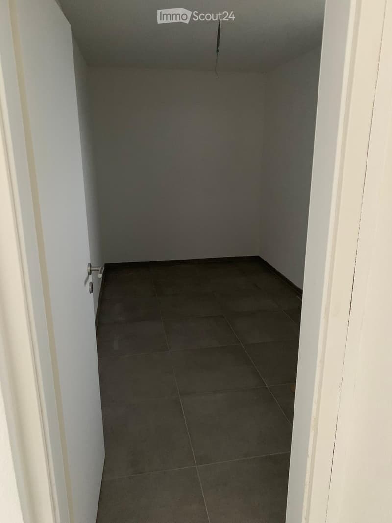 Empty hallway with tiled floor and white walls, featuring a door on the left side.