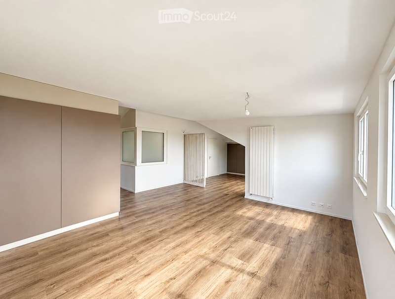 Empty room with wooden flooring, white walls, and large windows. No furniture or equipment present.