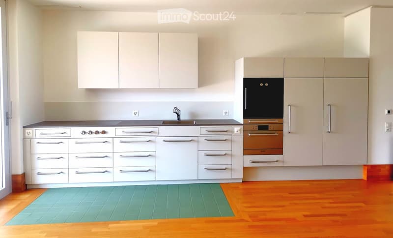 Modern kitchen with white cabinets, stainless steel appliances, and a wooden floor. Features a sink with a faucet, a stove, and an oven.