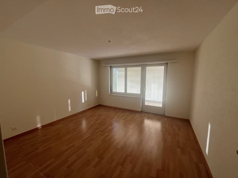 Empty room with wooden flooring, white walls, and a large window with blinds. No furniture or equipment is present.