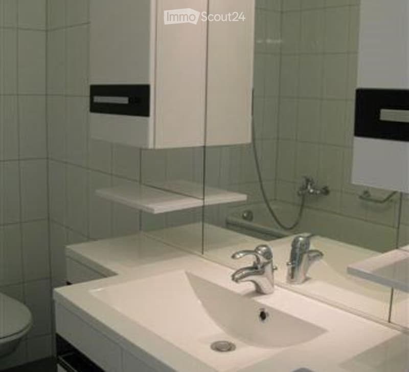 Tiled bathroom, sink, mirror, toilet, shower head, shower wall