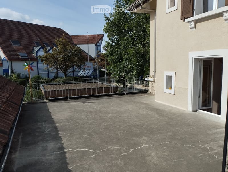 Balcony with metal railing, small wooden platform, and a colorful pinwheel decoration visible in the background.